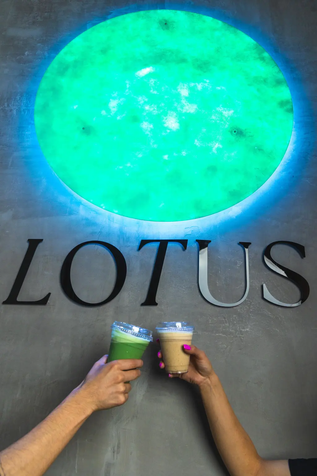 Muro de concreto con las letras LOTUS en acero y dos bebidas del Lotus Bar